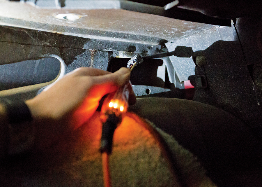 Identify a constant-power source in trunk or rear compartment with a test light. We found an orange wire that fed power to the dome light, which is perfect. After you’ve done that, disconnect the battery.